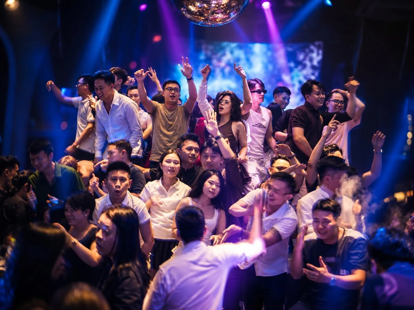 Đám đông nhảy dưới quả cầu disco và ánh đèn xanh tại 717